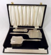 A silver backed dressing table set, comprised of a long handled hair brush, a smaller hair brush,