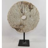 A large coral circular carved disc with central hole, (similar to that of a rai stone), raised on