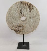 A large coral circular carved disc with central hole, (similar to that of a rai stone), raised on