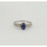 An 18 carat white gold lapis lazuli and diamond ring, the oval lapis lazuli cabochon in four claw