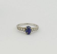 An 18 carat white gold lapis lazuli and diamond ring, the oval lapis lazuli cabochon in four claw