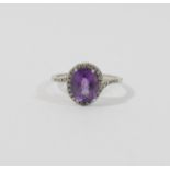 A 9 carat white gold amethyst single stone ring within melee diamond surround and shoulders,