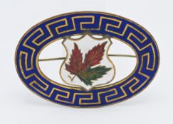 A large enamelled brooch decorated in Greek key cut border with a portal leaf centre unmarked metal,