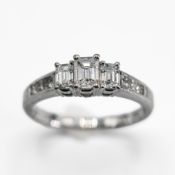An 18ct white gold ring set centrally with three emerald cut diamonds, total weight 0.80