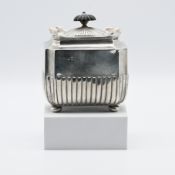 A silver tea caddy of octagonal shape with bun feet and hinged lid with a turned finial, London