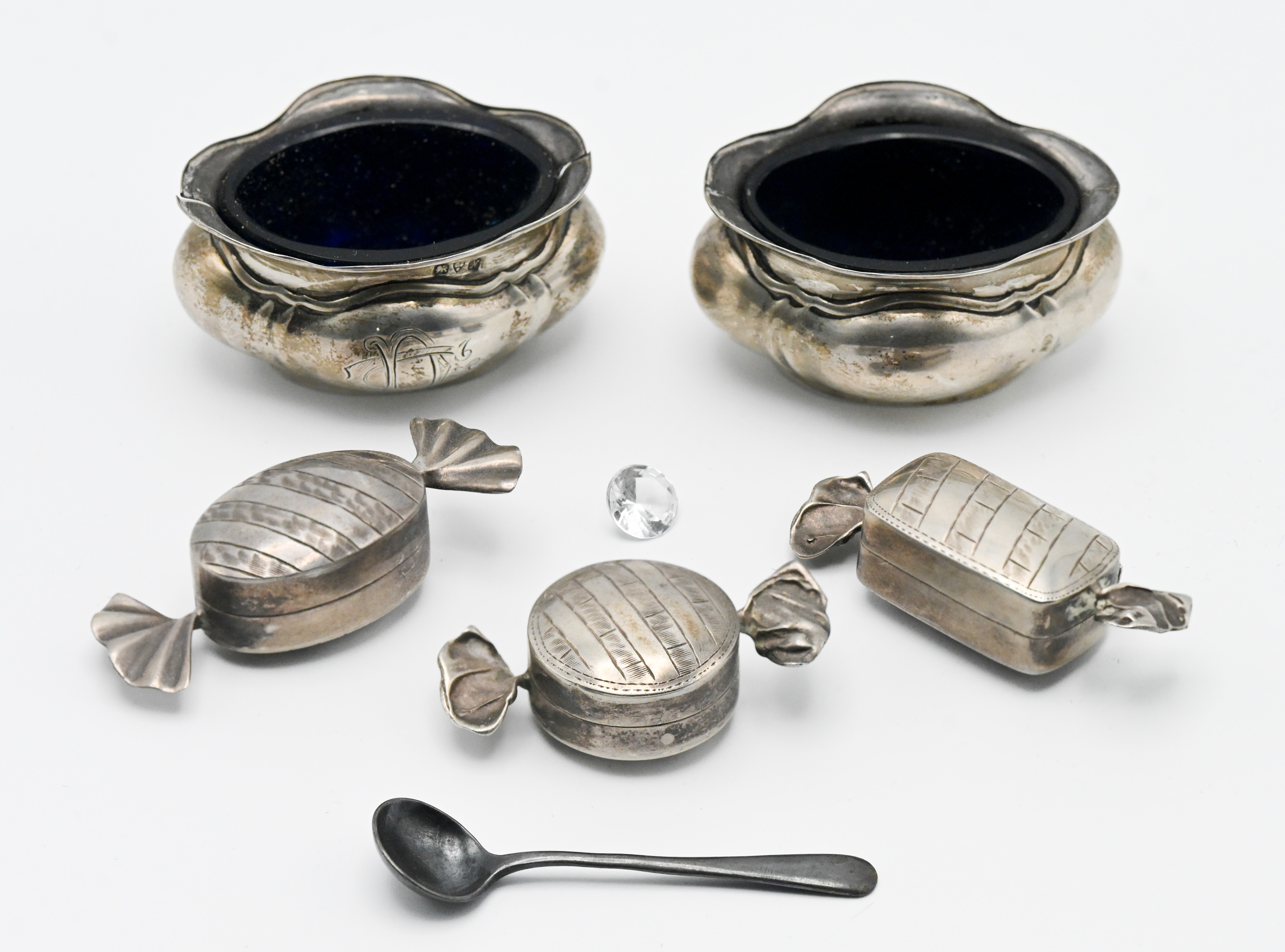 Three modern silver novelty pill boxes in the form of sweets together with a pair of silver salts