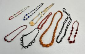 A small collection of dress jewellery including an Amber style bead necklace and other necklaces.