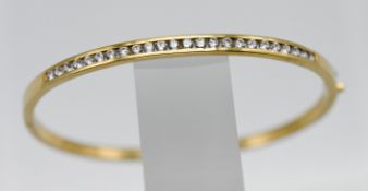 An 18ct yellow gold and diamond half snap channel set bangle, set with twenty four modern