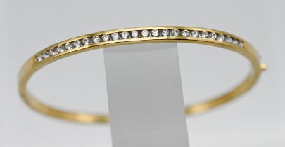 An 18ct yellow gold and diamond half snap channel set bangle, set with twenty four modern