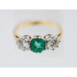 An emerald and diamond ring, centre trap cut emerald of good colour, two modern brilliant cut