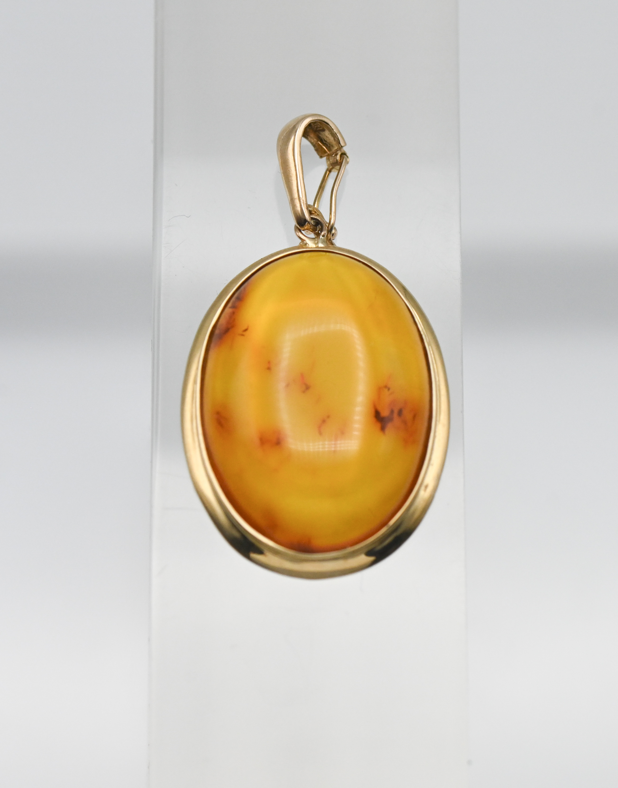 A Honey coloured Baltic amber gold (hallmark 585) pendant with some fossils naturally trapped in the