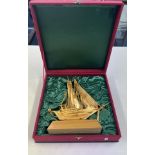 A gilt metal model of a twin masted ship on plinth. Height 28cm in fitted presentation case