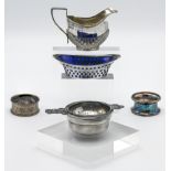 A small silver cream jug, two silver napkin rings, silver and pierced mustard dish with blue glass