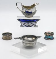 A small silver cream jug, two silver napkin rings, silver and pierced mustard dish with blue glass