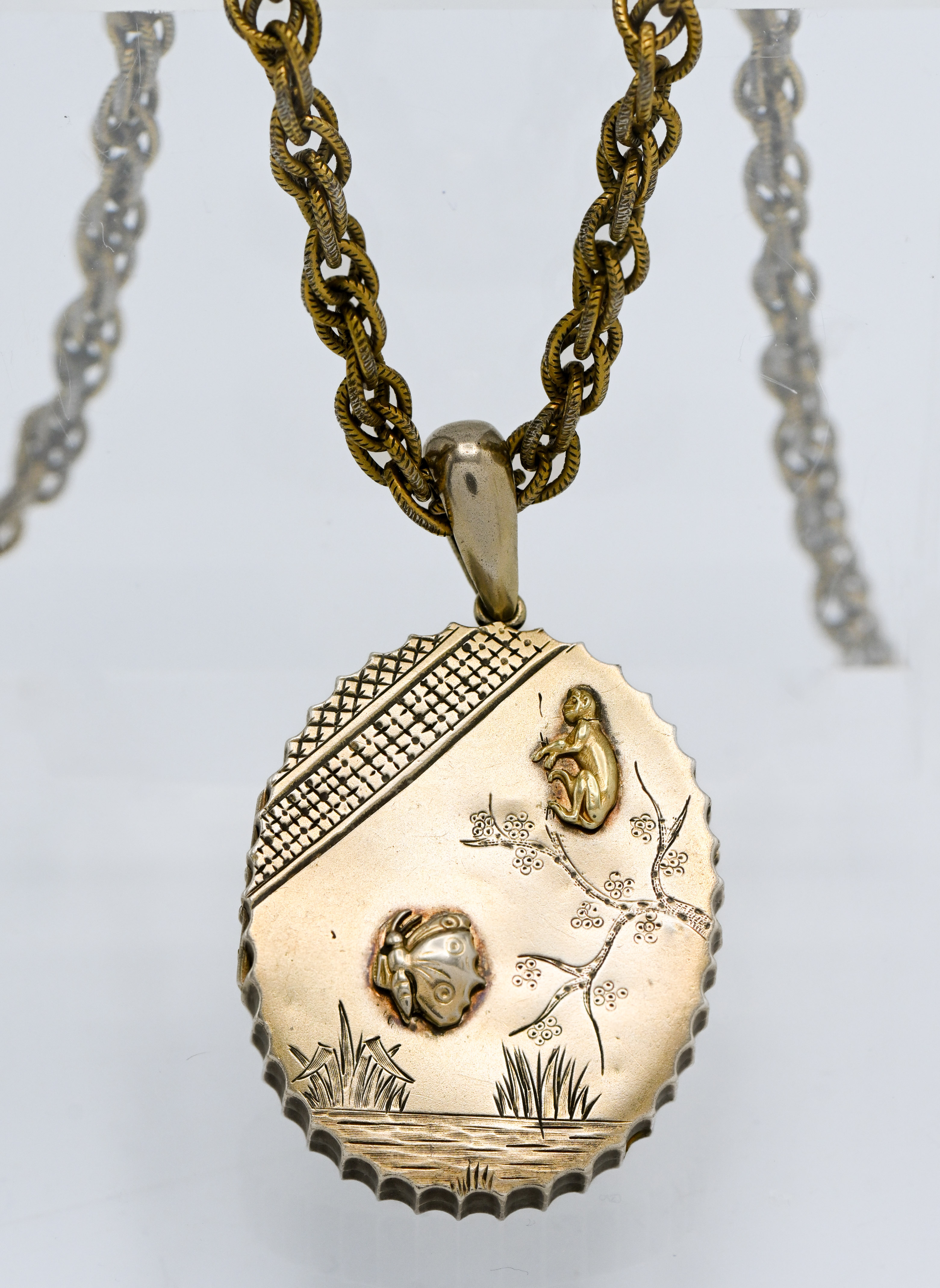 A silver gilt pendant lined with a mirror, on guilt rope twist chain with landscape and inset