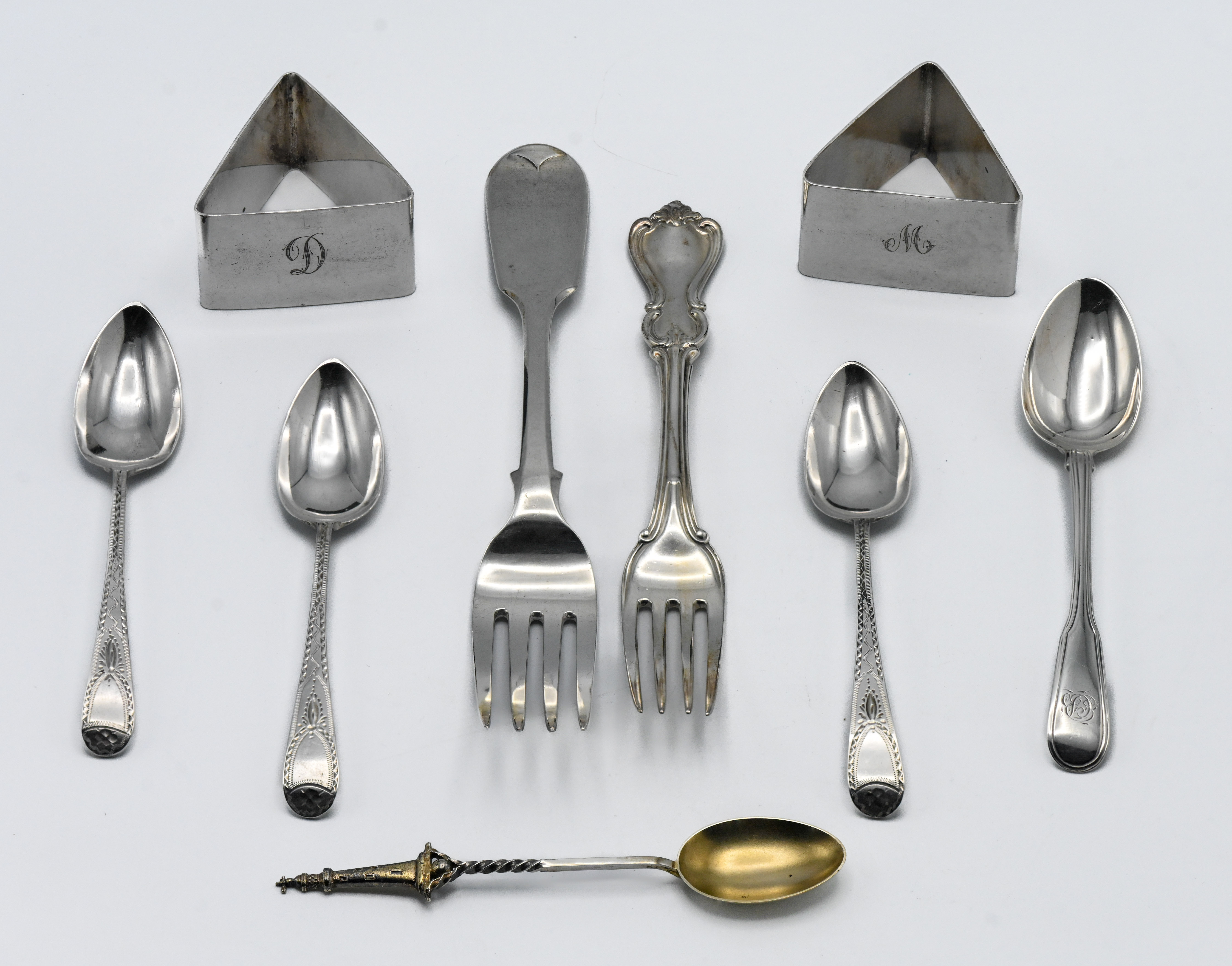 A pair of triangular napkin rings, together with flatware including Victorian forks, teaspoons