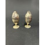 A pair of white metal novelty egg cups with bird head covers.