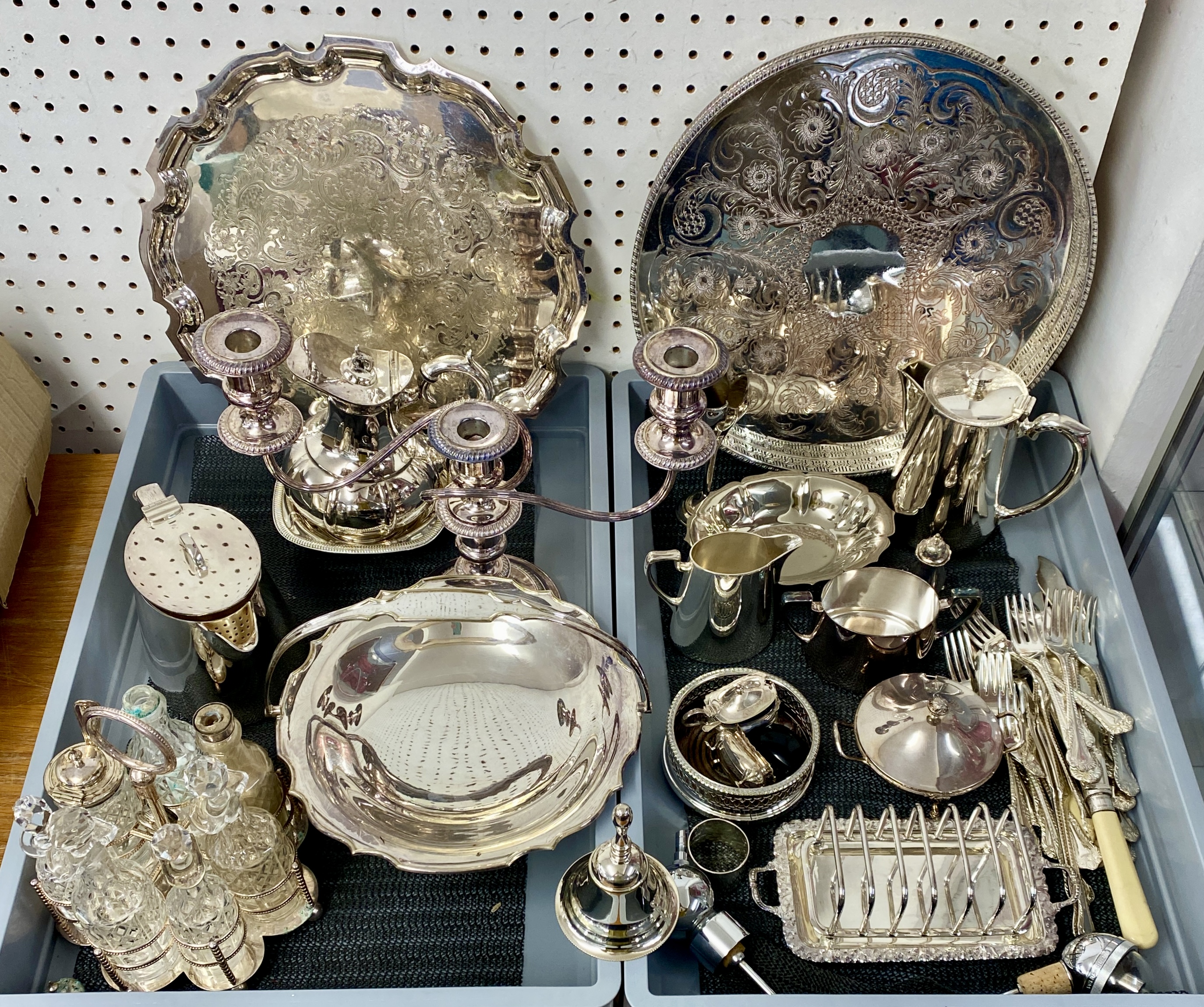 A quantity of silver plated wares including serving trays, candelabra, cake stands, seven bottle