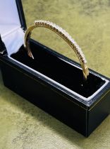 An 18ct yellow gold and diamond set bangle, approx. 17.8g, with purchase receipt dated 1990.