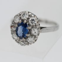 An 18ct sapphire and diamond cluster ring, the cornflower sapphire approx. 0.68ct set in white gold,