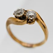 An 18ct two stone diamond cross over ring, size L/M.