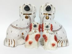 A pair of Staffordshire dogs, white with gilt details, height 23cm, together with a smaller pair,