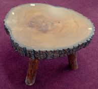 A wood coffee table, the surface made out of a single tree section with naturalistic bark rim, solid