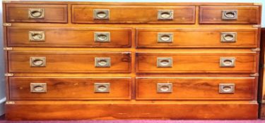 A yew campaign style sideboard, with recessed brass handles in nine drawers, on a plinth base,