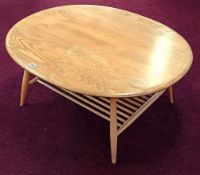An Ercol beech oval coffee table, with turned wood magazine rack, height 44cm, length 99cm