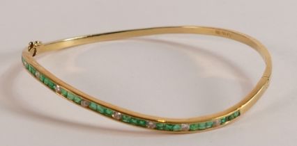 18ct gold diamond and emerald bangle, weight 8.4g.