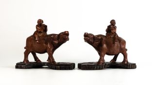 Pair of Chinese hardwood carvings, in the form of two figures riding buffalo on stands. Buffalo have