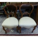 A pair of carved Walnut balloon back upholstered bedroom chairs with brass castors to front supports