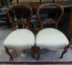 A pair of carved Walnut balloon back upholstered bedroom chairs with brass castors to front supports