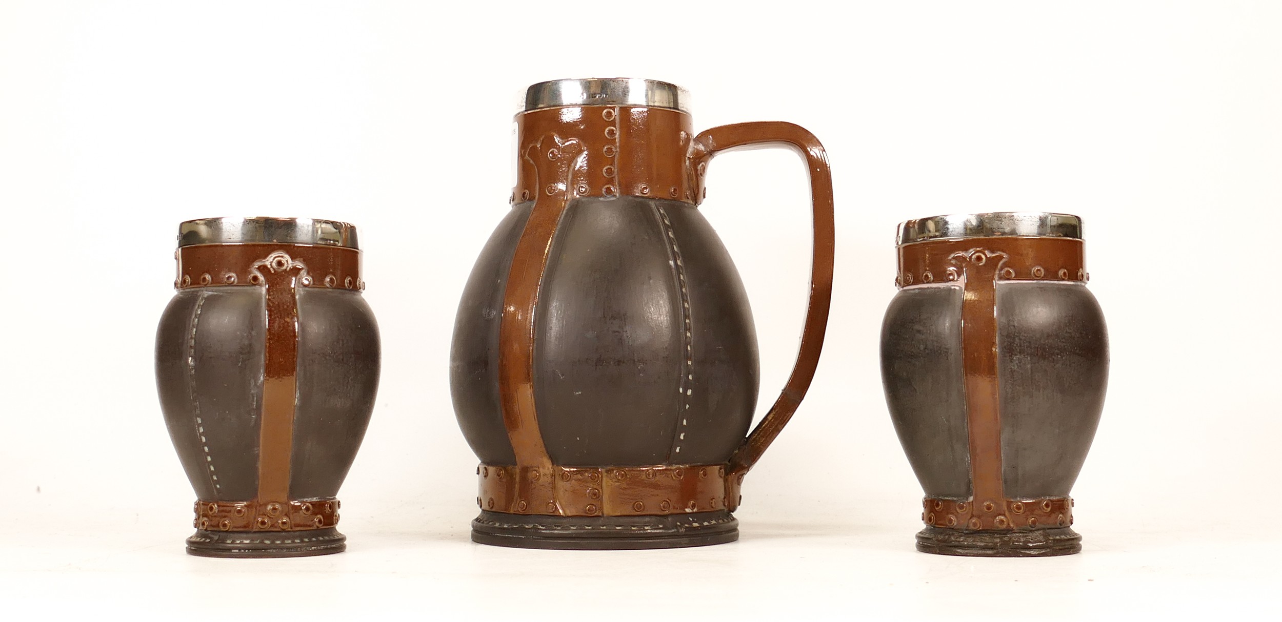 Doulton Lambeth Silver Rimmed Silicon Leather Ware Jug and Two Cups. Handle of Jug is restored