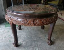 An Oriental Heavily Carved Glass Top Table on Four Ball and Claw Feet. Height: 52cm Diameter: