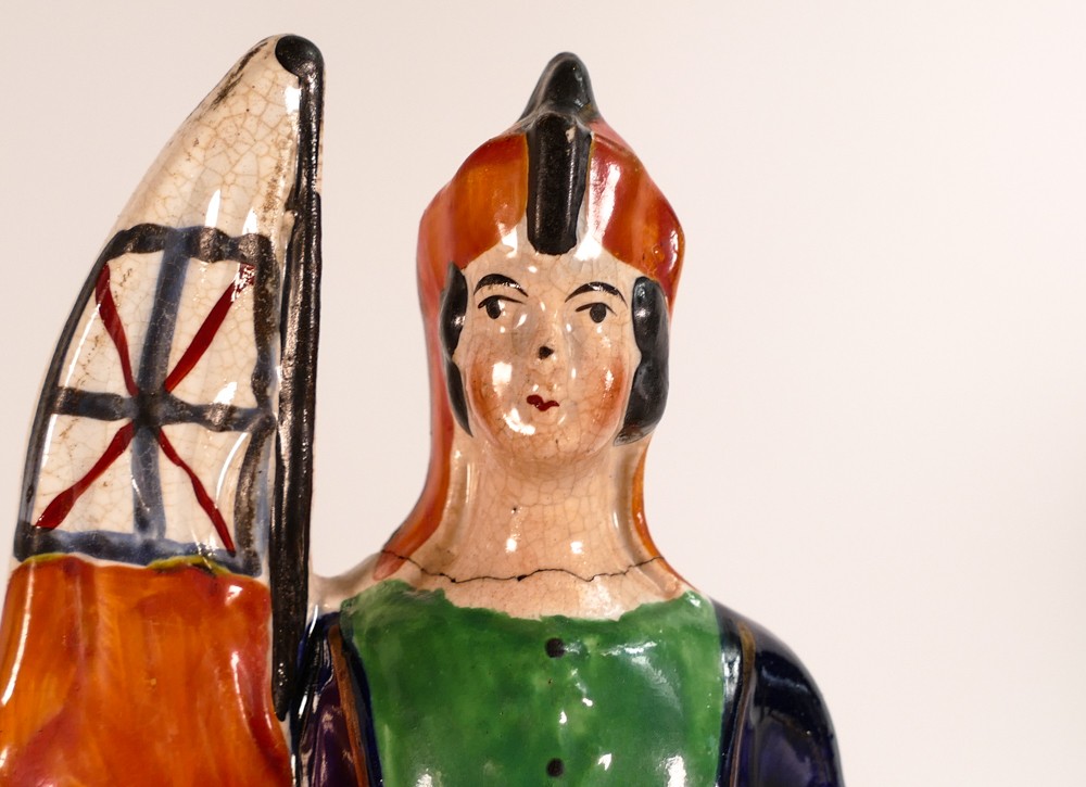 Staffordshire military themed figure bearing an orange flag with sword and shield in hand, re- - Image 3 of 4