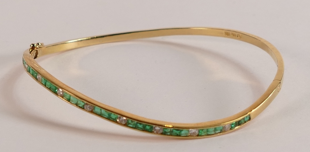 18ct gold diamond and emerald bangle, weight 8.4g.