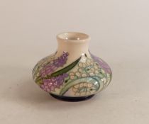 A Moorcroft squat vase decorated in purple and white flowers on blue/white ground, signed, dated