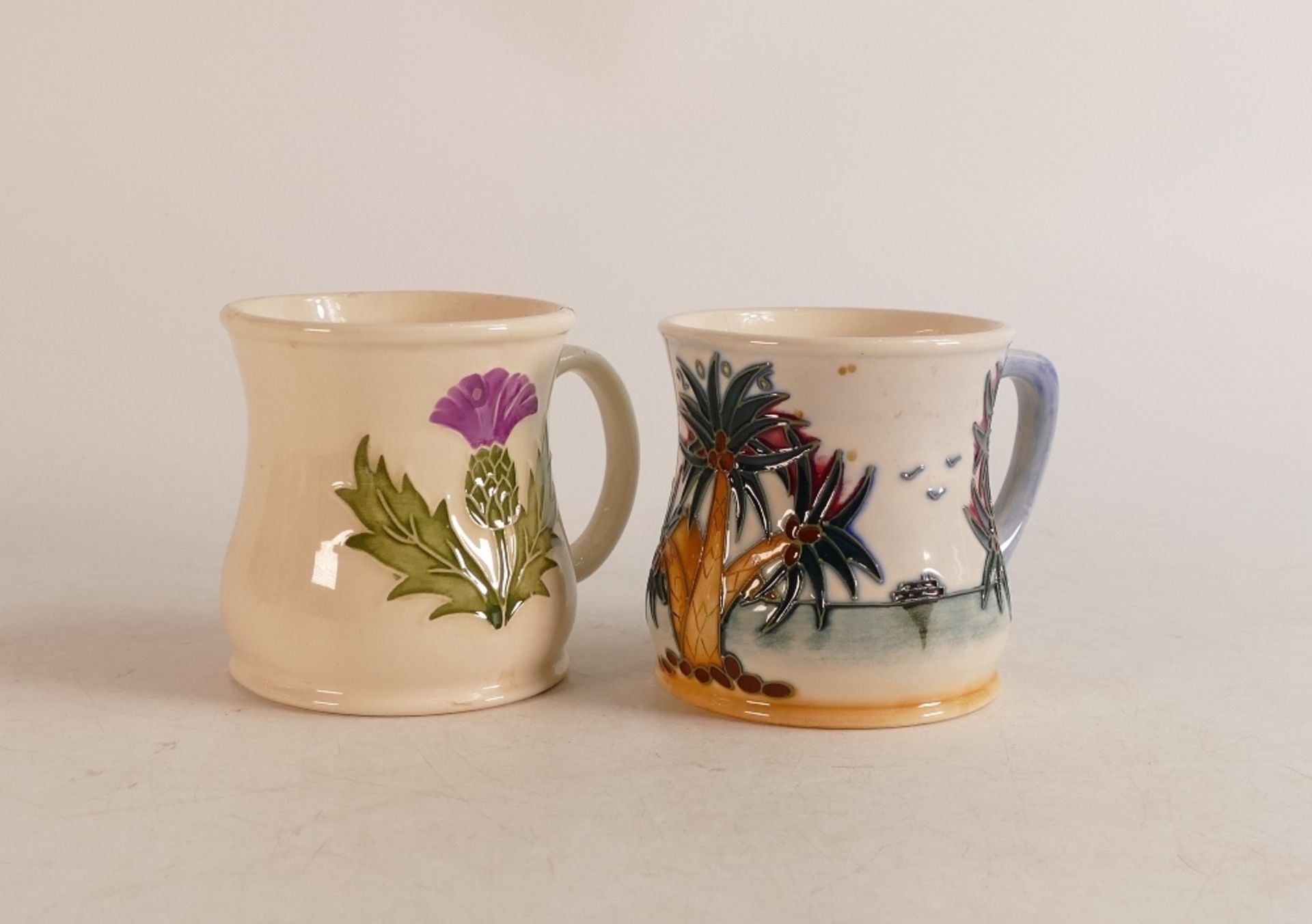 Two Moorcroft mugs to include Thistle (crazing and staining inside) and Palm Tree (2)