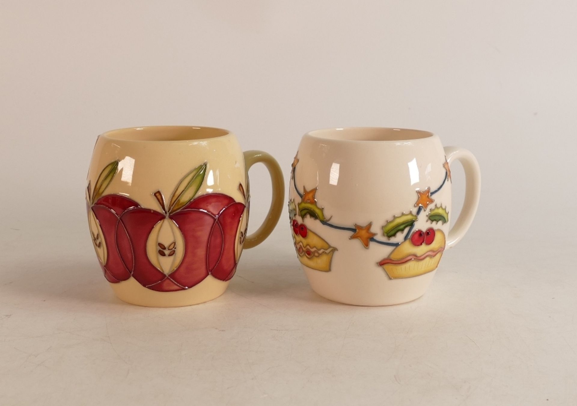 Two Moorcroft Mugs to include Apple and Christmas mug decorated with pies, holly and stars (2)