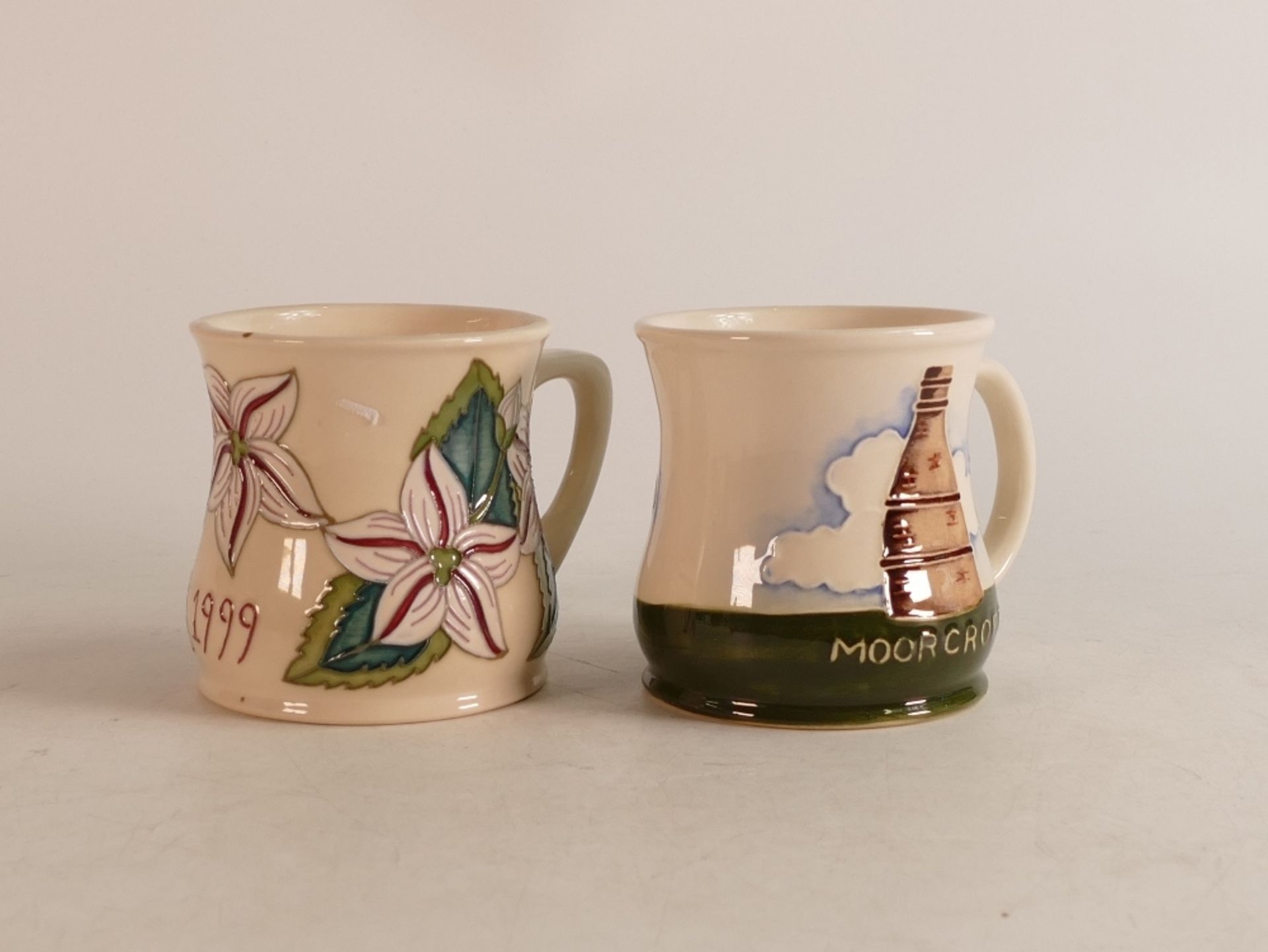 Two Moorcroft mugs to include Moorcroft factory and 1999 year mug (2)