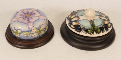 Two Moorcroft paperweights in the purple pansy pattern and wild flora decorated paperweight
