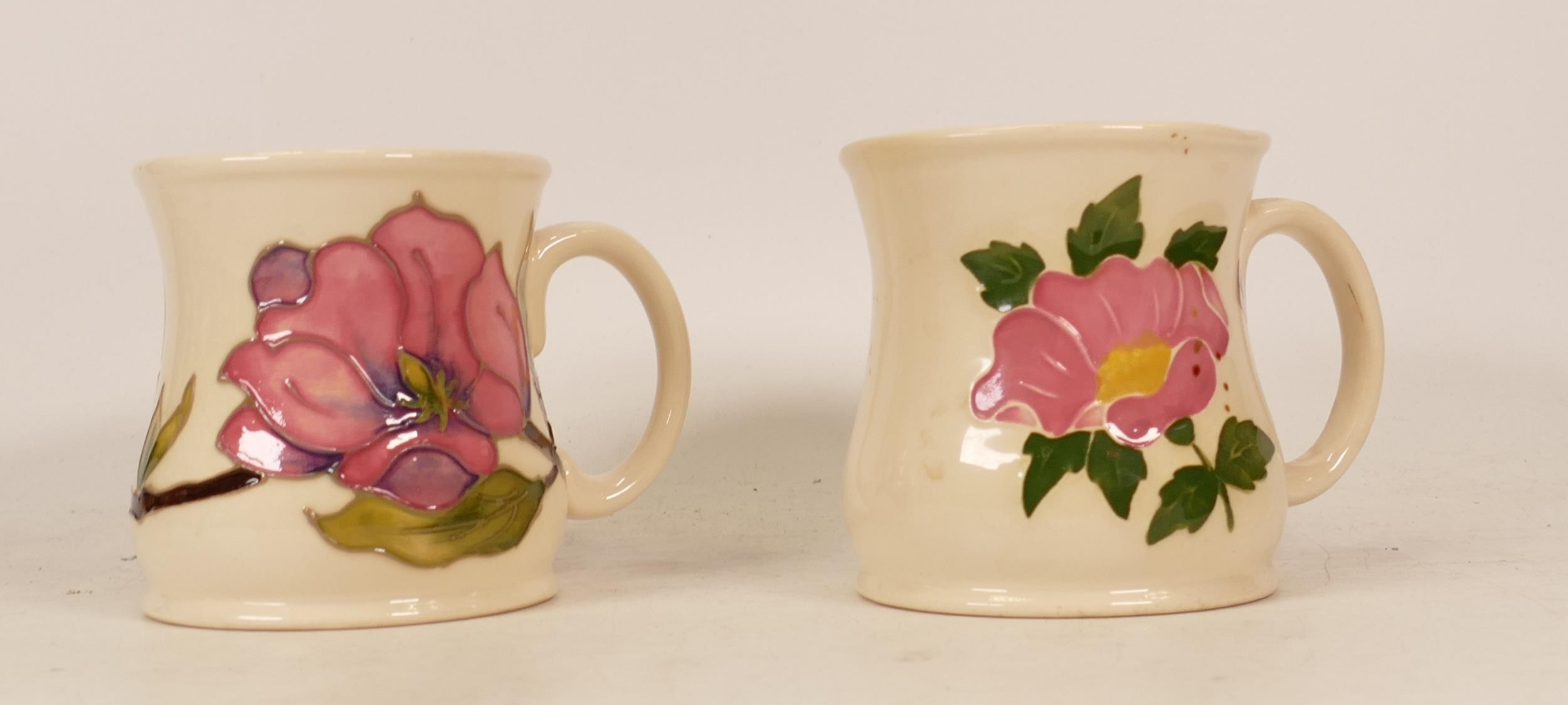 Moorcroft mug of the year 1987 (a/f) and Moorcroft mug decorated with a pink flower (2)