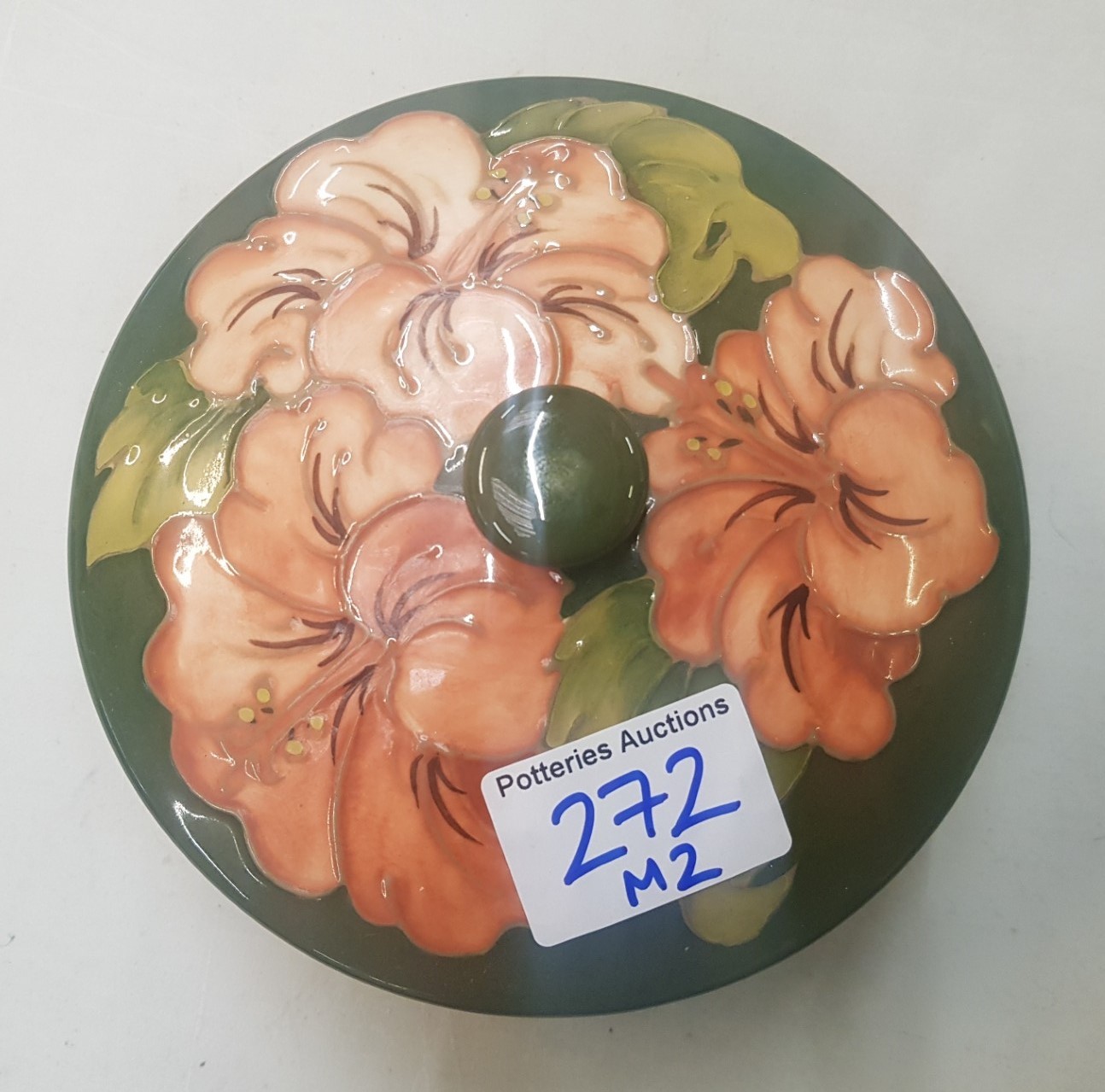 Moorcroft Hibiscus on green ground round lidded pot 14cm in diameter.