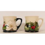 Moorcroft mug decorated with Holly and Berries together with a mug decorated in white flowers with