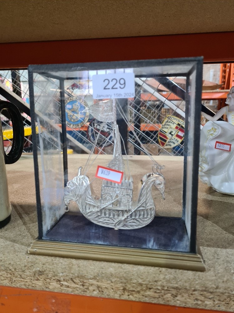 A white metal filigree ship in the form of a bird in glass case