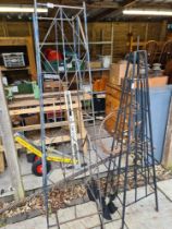 An iron pole with 6 arms for hanging baskets and 2 garden obelisks