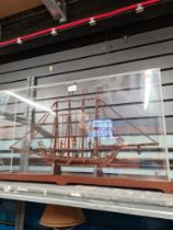 A scratch-built folk art style boat in a perspex case