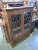 A reproduction oak bookcase having leaded glass doors and cupboard below