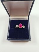 Contemporary white gold dress ring with central pear cut ruby in 3 claw mount, 5 x 7mm with a circul